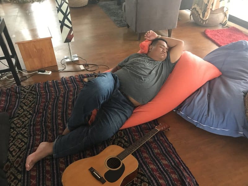 Asad Zulfahri sleeping on a beanbag next to a guitar